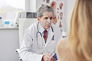 Senior doctor talking with woman in doctorÃ¢â¬â¢s office photo